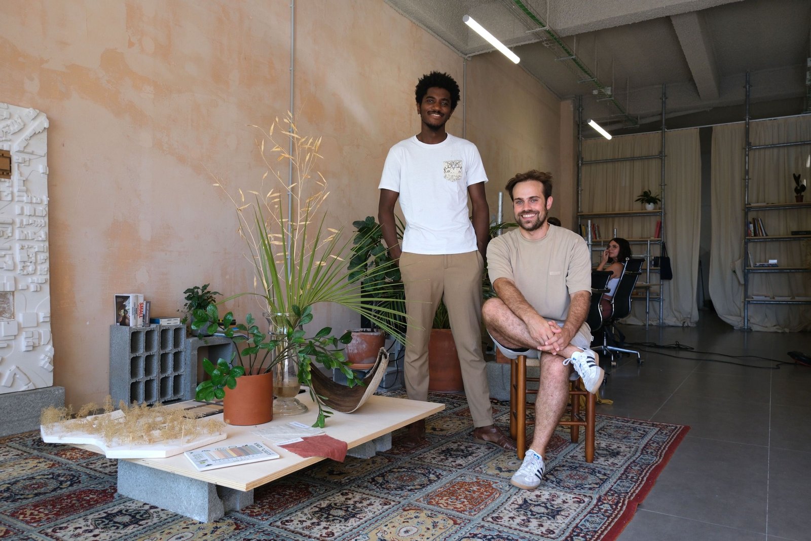 The two Cova architects in the studio, beside a model and material samples.